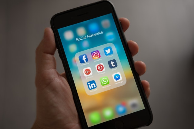 Hand holding smartphone displaying social media icons